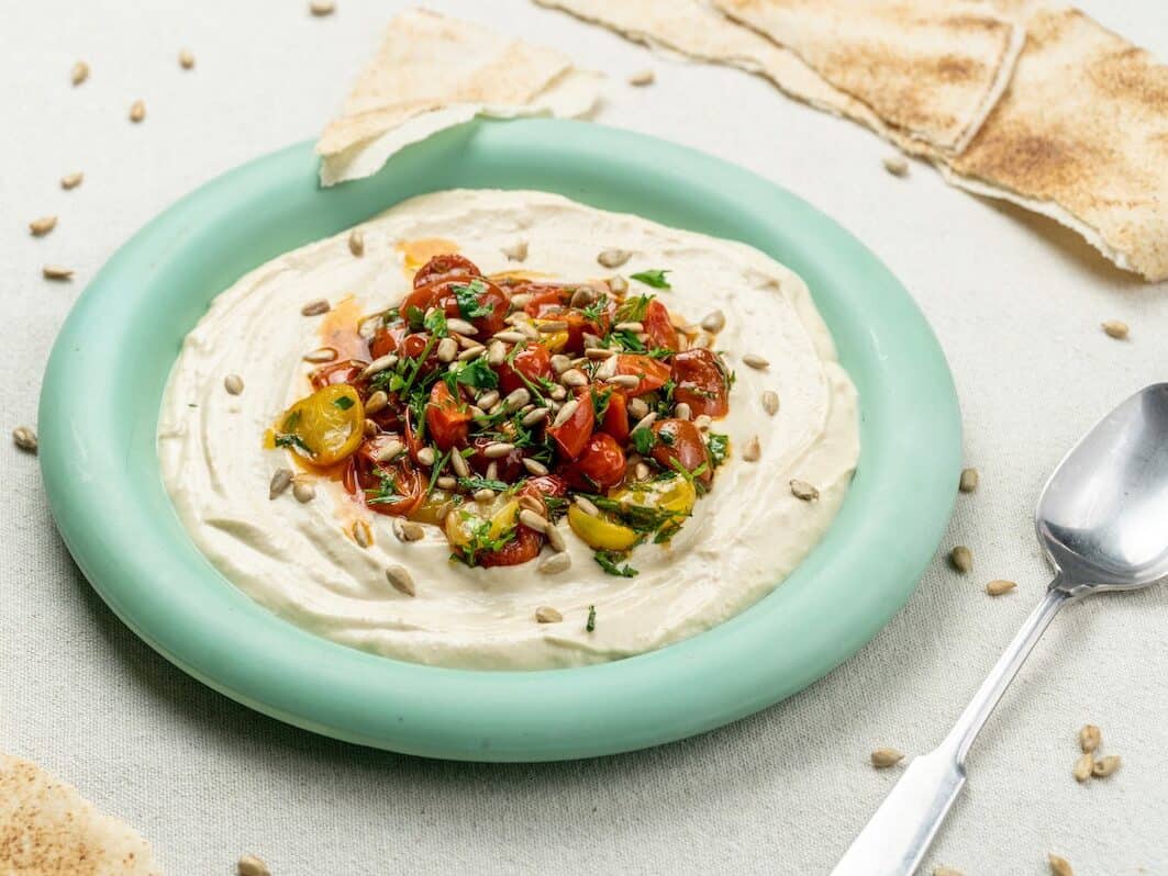 farfurie cu hummus labneh și roșii coapte cu verdețuri